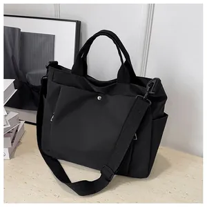 Détails d'un grand sac cabas en nylon noir avec bandoulière réglable et poches latérales