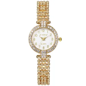 Detail einer goldenen Damenuhr mit Strass-Lünette und markantem Perlenarmband