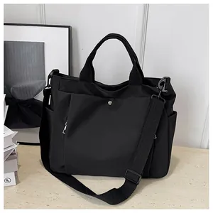 Détail du grand sac cabas noir en toile avec poche à bouton pression et bandoulière
