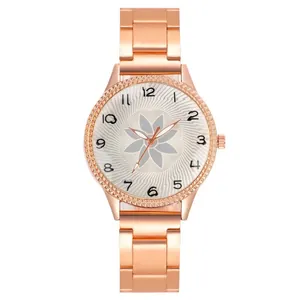 Close-up of rose gold watch with floral pattern dial and Arabic numeral markers
