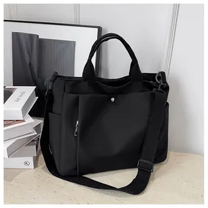 Vue détaillée du cabas en nylon noir avec poche à pression et bandoulière amovible réglable