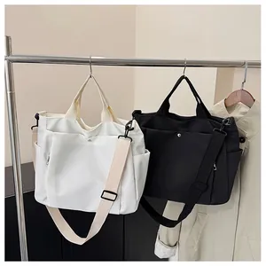Détail de grands sacs fourre-tout en nylon noir et blanc avec des poches latérales