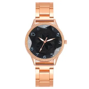 Detail of rose gold metal watch band and black dial with floral relief pattern