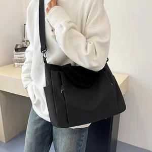 Grand sac fourre-tout noir en toile porté en bandoulière pour le travail ou les cours