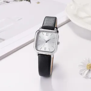 Macro shot of square silver dial with black leather strap on a minimal white background