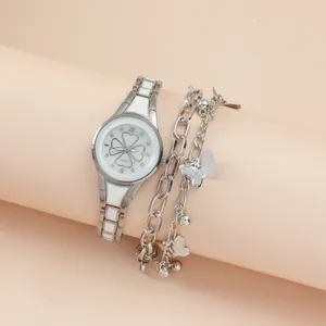 Silver clover watch and butterfly bracelet set displayed on elegant pink stands