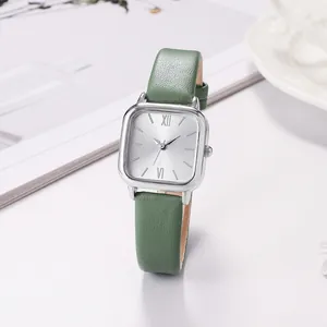 Vintage square women's quartz watch with green leather strap on a minimalist desk