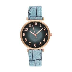 Detailed close-up of rose gold watch case with leaf pattern dial and blue leather strap