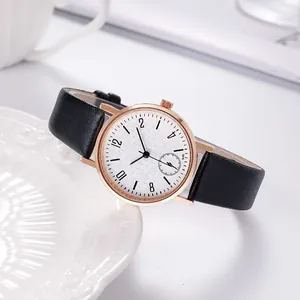 Macro detail of rose gold watch case with white patterned dial and black leather strap