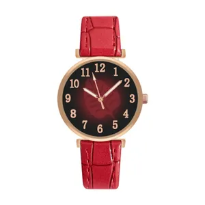 Detail view of red faux-crocodile leather strap and rose gold leaf pattern watch dial