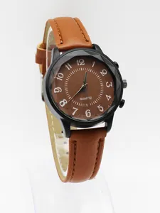 Macro detail of brown leather strap and faceted matte black case of woman's quartz watch