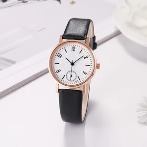 Detail of rose gold watch face featuring delicate snowflake patterns and black leather strap