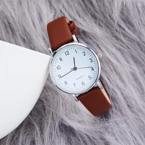 Detail shot of a minimalist quartz watch with white dial and brown leather strap on plush
