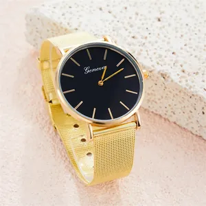 Detailed close-up of gold mesh strap and black dial Geneva watch on stone display