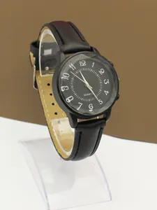 Detail of minimalist black quartz watch with leather strap and white Arabic numerals