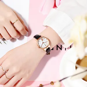 Detail of rose gold cat-ear watch with black leather strap and feline dial pattern