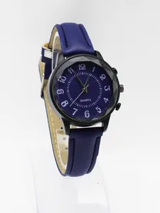 Macro shot of blue textured watch dial with white numerals and faceted crystal glass