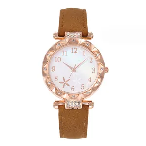 Detail of rose gold starfish watch face with floral patterns and a brown leather strap