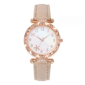 Detail of rose gold scalloped bezel with crystals and beige leather strap on watch