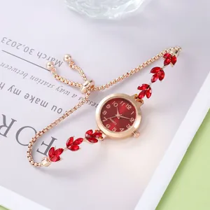 Détail d'une montre bracelet dorée ajustable avec cristaux de feuilles rouges et cadran