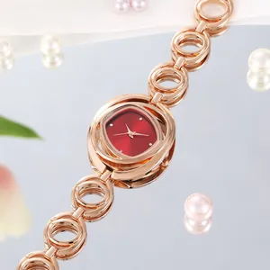 Elegante roségouden horloge met opengewerkte kettingschakels en een rode kussenvormige wijzerplaat