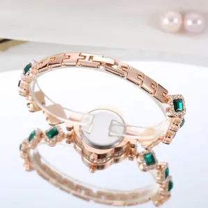 Detailed close-up of a rose gold luxury watch with green gemstones and fine diamond accents
