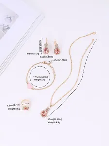 Detail van een gouden sieradenset met oranje stenen en roze hartvormige hanger