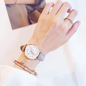 Close-up of women's heart watch with grey leather strap and rose gold star jewelry