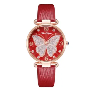 Detail of red leather watch strap with rose gold butterfly pattern and sparkling dial