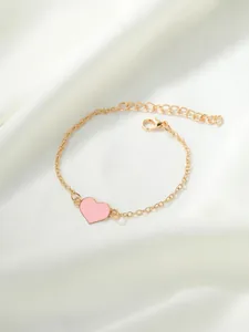 Vista dettagliata di un bracciale dorato con ciondolo a cuore rosa su seta bianca