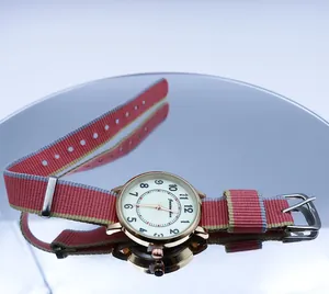Close-up of luminous quartz watch with rose gold case and striped NATO nylon strap
