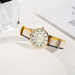 Detail of minimalist women's watch with gold case and striped nylon canvas strap