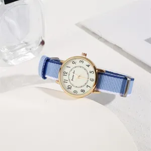 Close-up of minimalist gold quartz watch with white numeric dial and blue-white nylon strap