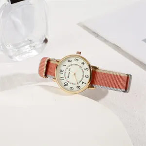 Detail of minimalist quartz watch with cream dial and striped nylon strap on a white stand