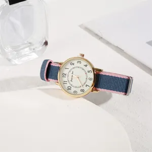 Detail of round gold watch with Arabic numerals and pink blue nylon strap