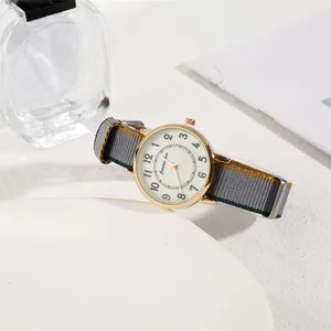 Detailed close-up of a minimalist round gold watch with a striped nylon NATO strap