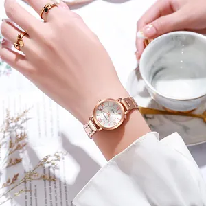 Détail d'une montre à quartz en or rose au poignet avec marbre et décor de café matinal