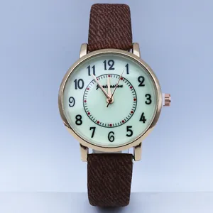 Detail view of quartz watch with Arabic numerals and brown canvas strap for women
