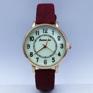 Detailed macro view of gold quartz watch case with green dial and red textured strap