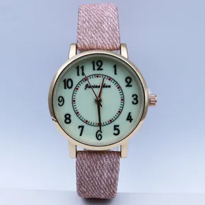 Detail of small quartz watch with green dial and pink woven strap for students