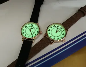 Macro shot of luminous round watches with glowing dials and leather straps in the dark