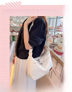 Close-up of a white waterproof crossbody bag with dual front zipper pockets and logo detail