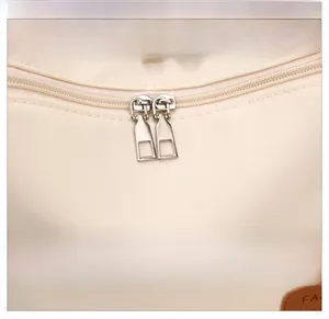 Detail view of beige waterproof dumpling bag showing dual metal zippers and woven fabric