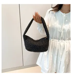 Detail view of black quilted fabric handbag with textured 3D floral pattern on model