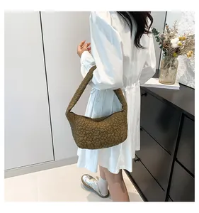Détail d'un sac sous le bras matelassé marron foncé avec texture florale en relief