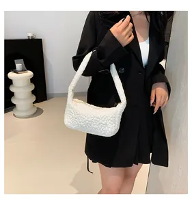 Gros plan d'un sac hobo blanc avec texture florale matelassée sur l'épaule du modèle