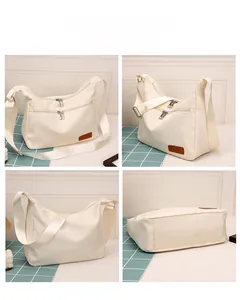 Detail view of cream dumpling bag showing double front zippers and fabric texture