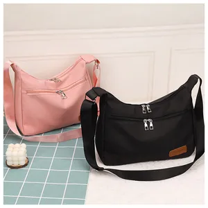 Waterproof crescent bags in pink and black featuring wide woven adjustable shoulder straps