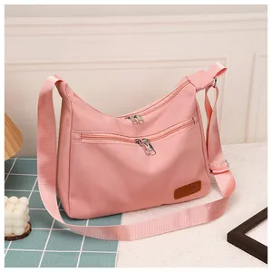 Detail shot of pink waterproof crossbody dumpling bag with twin zippers and leather fashion tag