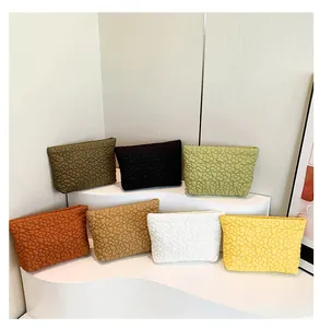 Quilted floral texture clutch bags displayed in seven vibrant colors on a white wavy stand